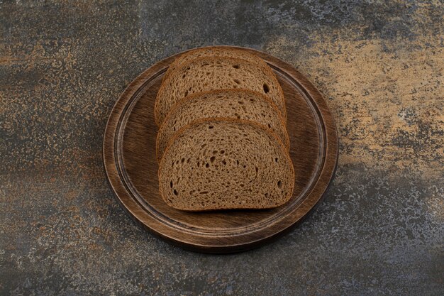 Rebanadas de pan negro casero sobre tabla de madera