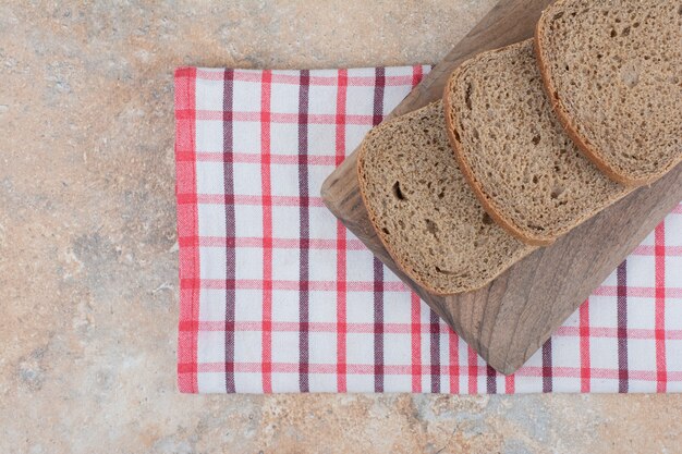 Rebanadas de pan negro sobre tablero de madera con mantel