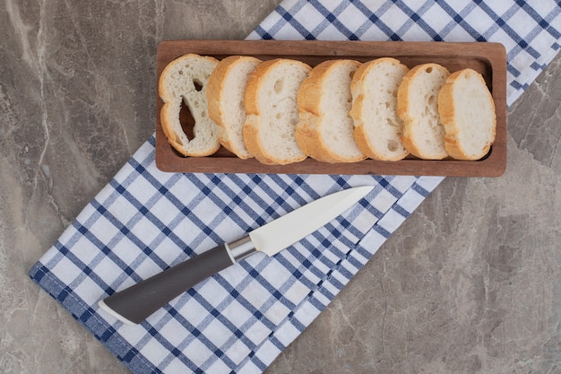 Rebanadas de pan en placa de madera con cuchillo. Foto de alta calidad