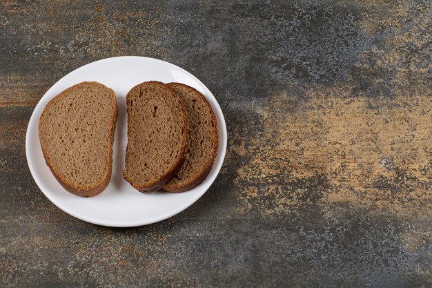 Rebanadas de pan sabroso en la placa blanca.