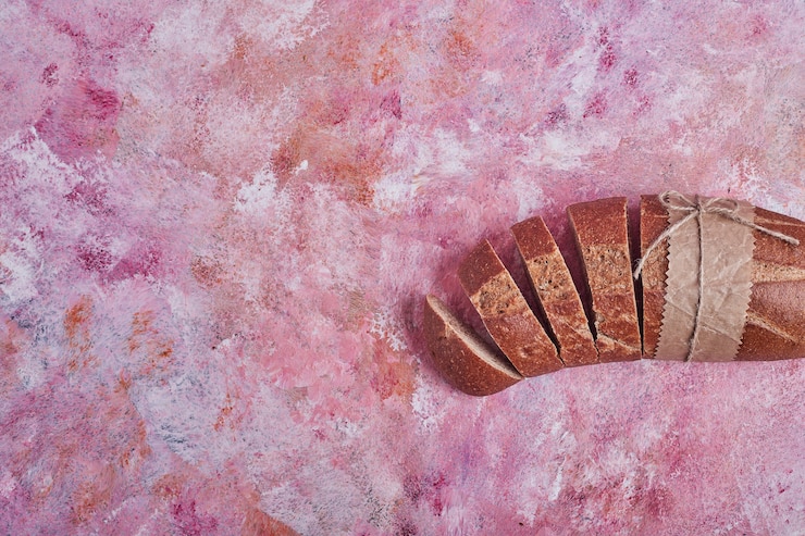 Foto gratuito rebanadas de pan sobre una mesa rosa.