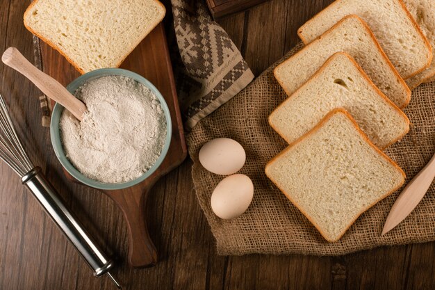 Rebanadas de pan y tazón de harina con huevos