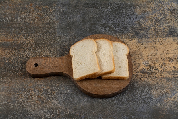 Foto gratuita rebanadas de pan tostado blanco sobre tabla de cortar de madera