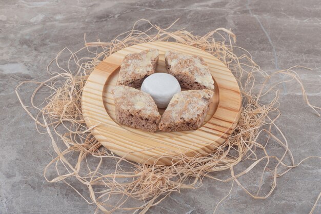 Rebanadas de pastel alrededor de una galleta recubierta de polvo de vainilla sobre una placa de madera sobre mármol