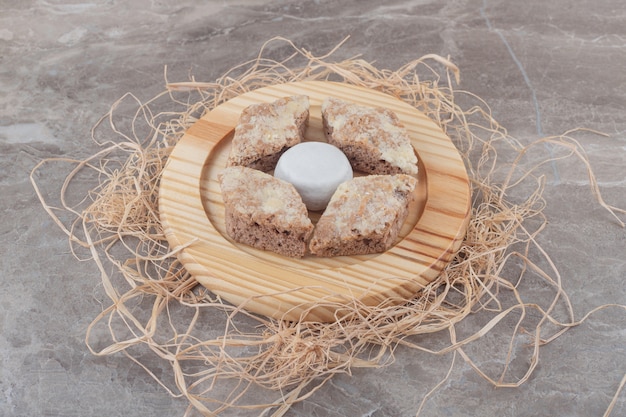 Rebanadas de pastel alrededor de una galleta recubierta de polvo de vainilla sobre una placa de madera sobre mármol