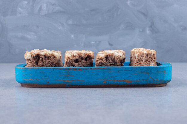 Rebanadas de pastel en una bandeja de madera sobre mármol