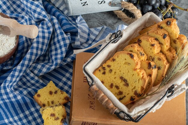 Rebanadas de pastel con pasas en canasta con uvas y mantel