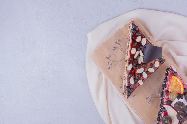 Rebanadas de pastel de triángulo con chocolate y frutas sobre una tabla de madera