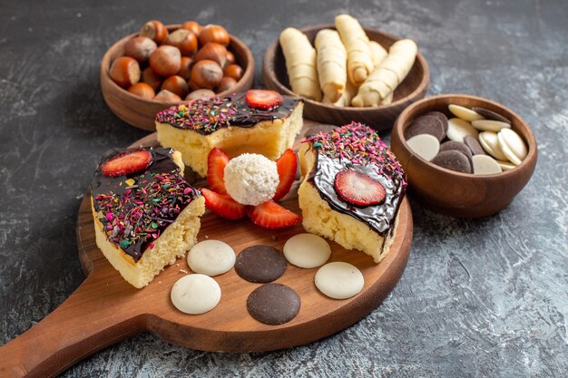 Rebanadas de pastel de vista frontal con nueces y galletas sobre fondo oscuro