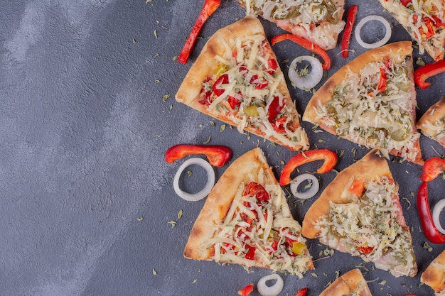 Rebanadas de pizza sabrosa en azul con aros de cebolla y pimiento.