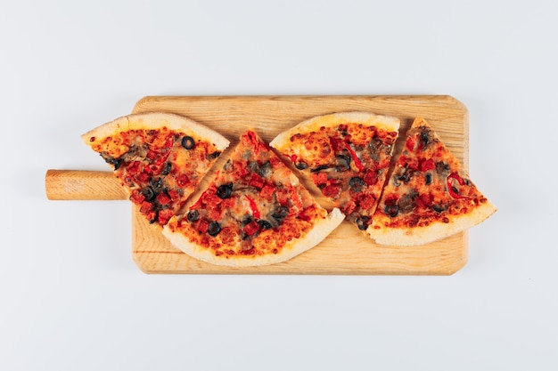Foto gratuita rebanadas de pizza en un tablero de pizza sobre un fondo de estuco blanco brillante. aplanada