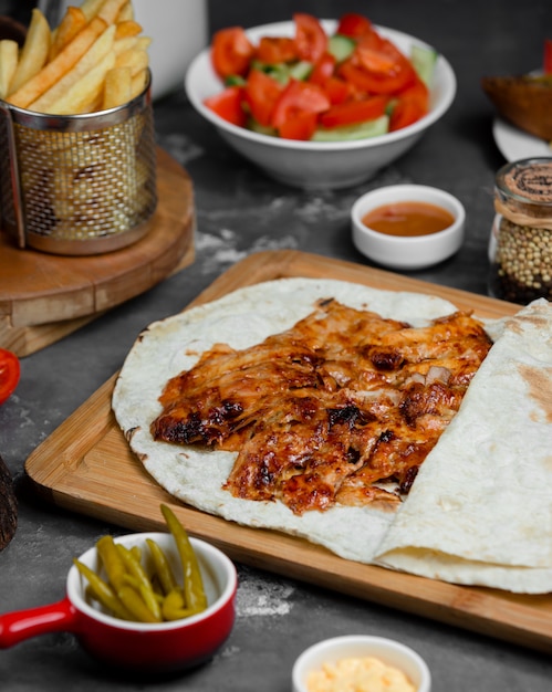 rebanadas de pollo a la parrilla dentro de la envoltura de lavash servidas con papas fritas