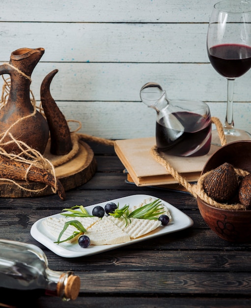 rebanadas de queso blanco adornadas con uva y estragón servidas con vino tinto