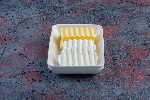 Rebanadas de queso blanco y mantequilla en un plato blanco.