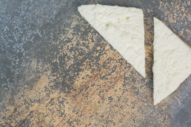 Rebanadas de queso blanco sobre mármol.