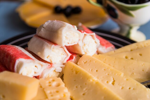 Rebanadas de queso fresco cerca de sabrosos aperitivos en un plato