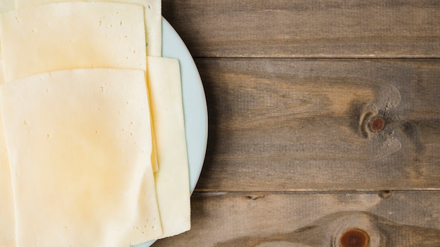 Rebanadas de queso en un plato blanco con fondo de tablones de madera