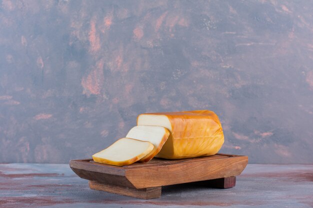 Rebanadas de queso rectangular sobre una tabla, sobre el fondo de mármol.