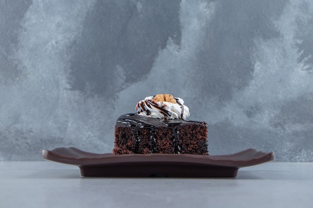 Rebanadas de sabroso brownie de chocolate con crema en un plato oscuro