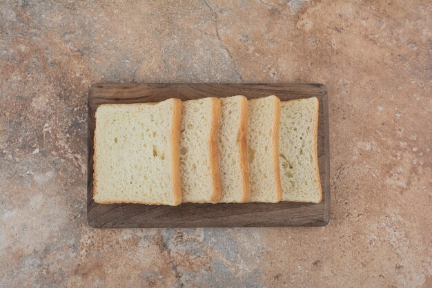 Rebanadas de tostadas blancas sobre tabla de madera