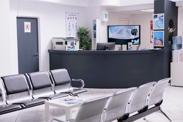 Recepción clínica con sala de espera en vestíbulo de instalaciones, mostrador de registro utilizado para pacientes con citas médicas. Mostrador de recepción vacío en el centro de salud para visitas de control.