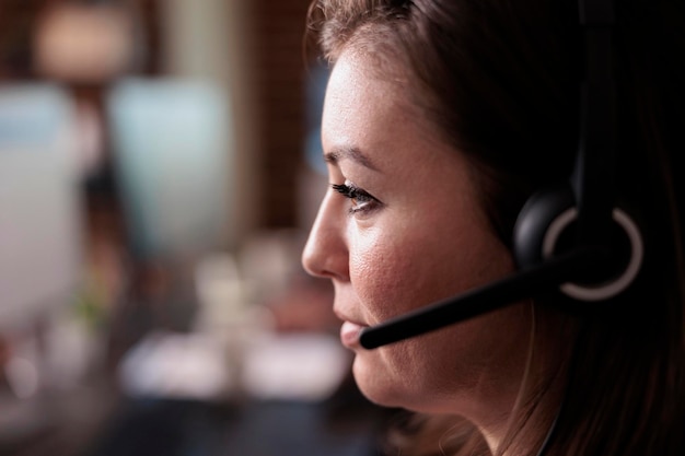 Recepcionista femenina con auriculares para trabajar en el servicio de asistencia del centro de llamadas, brindando asistencia de telemercadeo. Mujer que trabaja en el servicio de atención al cliente para ayudar a los clientes, red de telefonía. De cerca.