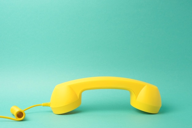 Receptor de teléfono amarillo sobre fondo turquesa