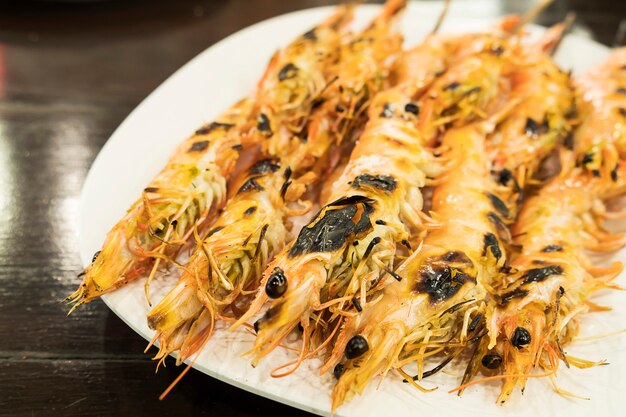 Receta de camarones a la parrilla servida en plato blanco sobre mesa de madera