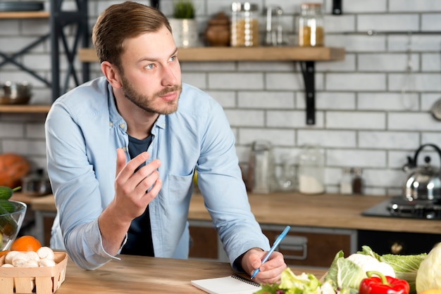 Foto gratuita receta de escritura de hombre pensativo en cocina