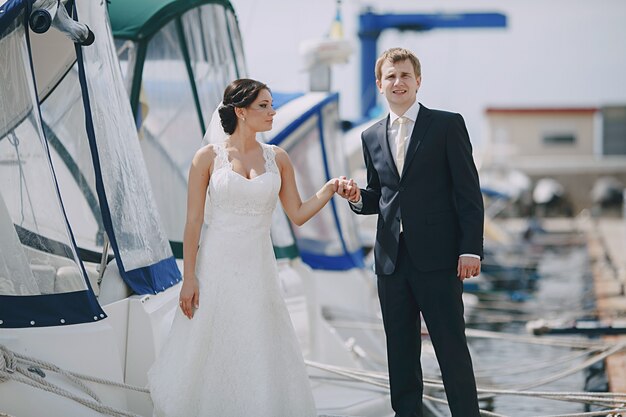 Recién casados agarrados de la mano en el puerto