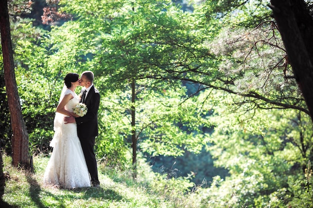Recién casados besándose en el bosque