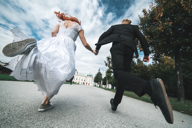 Recién casados corriendo a lo largo de la carretera