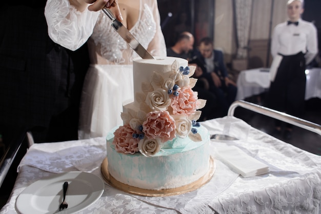 Los recién casados están cortando el pastel de bodas