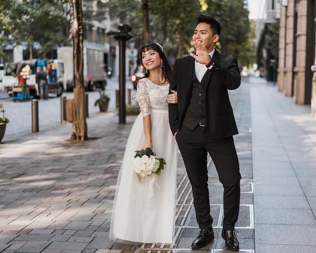 Recién casados posando juntos en la calle