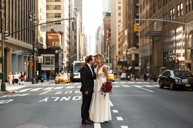 Los recién casados ​​que abrazan se colocan en el medio de la calle en New York City