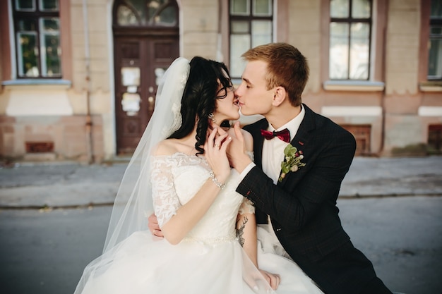 Recién casados ​​recién casados ​​besándose en la calle