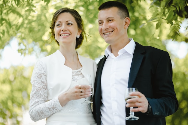 Los recién casados sonríen y mantienen copas con champaña