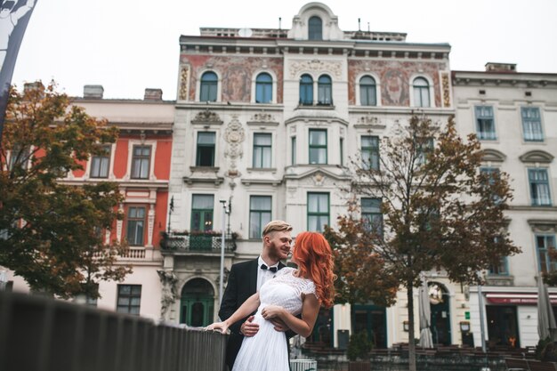 Recién casados sonrientes posando junto a una barandilla