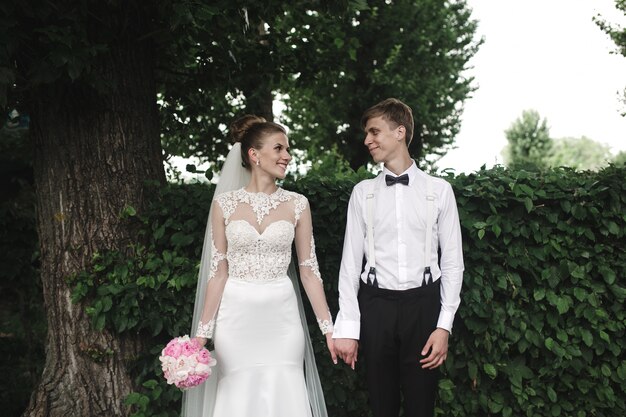 Recién casados sonrietes con la naturaleza de fondo