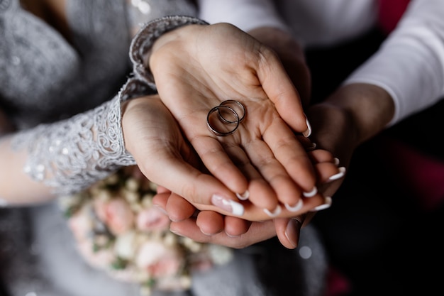 Los recién casados sostienen los anillos de boda en sus manos