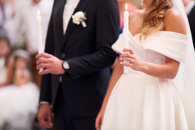 Recién casados con velas durante la ceremonia de compromiso en la iglesia