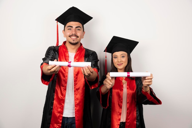 Foto gratuita recién graduados mostrando su diploma en blanco.