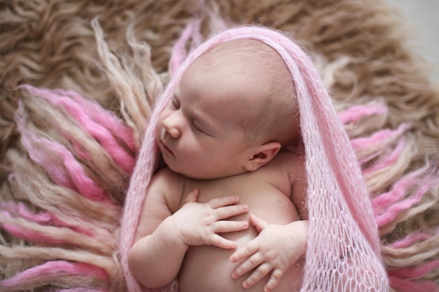 Recién nacida durmiente suave rosa sobre lana beige