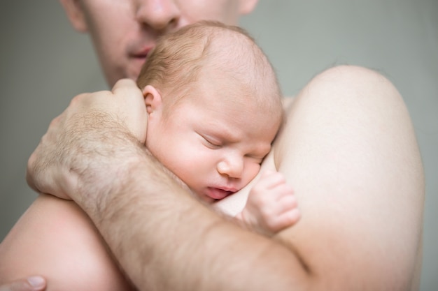 Recién nacido durmiendo en brazos masculinos