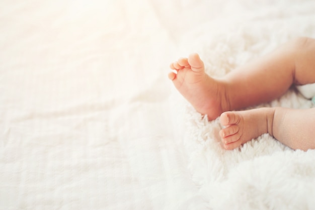 Foto gratuita recién nacido piernas del bebé en la cama de color blanco.