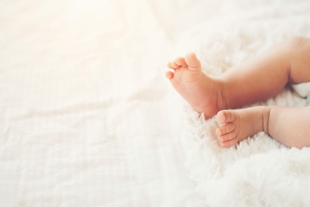 Recién nacido piernas del bebé en la cama de color blanco.