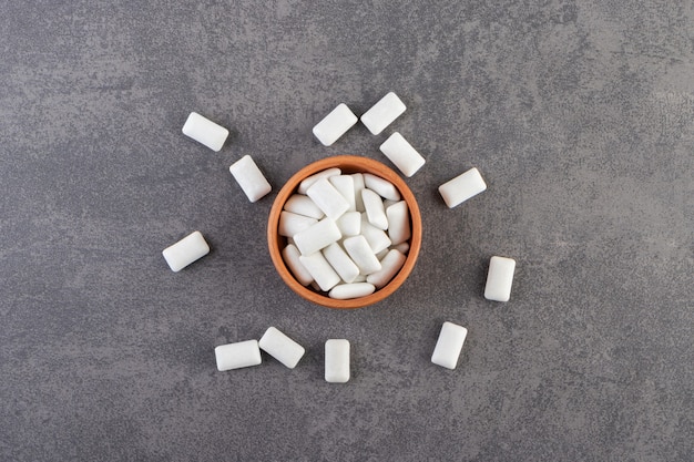 Foto gratuita recipiente de arcilla lleno de chicles blancos colocados sobre una mesa de piedra.