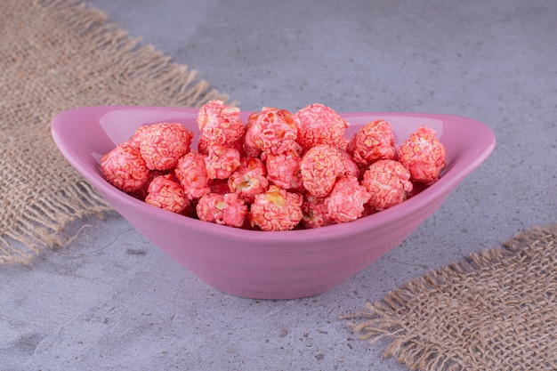 Foto gratuita recipiente de cerámica de bolas de palomitas de maíz rosa sobre la superficie de la piedra