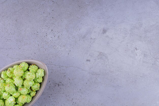 Recipiente gris lleno de dulces de palomitas de maíz sobre fondo de mármol. Foto de alta calidad