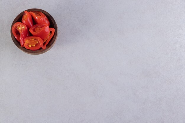 Recipiente de madera de tomates en escabeche colocados sobre la mesa de piedra.